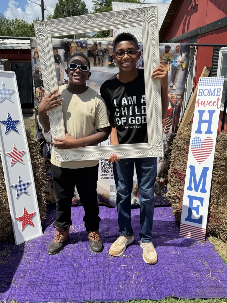 Two boys pose together inside the Know More Tears photo frame at the carnival