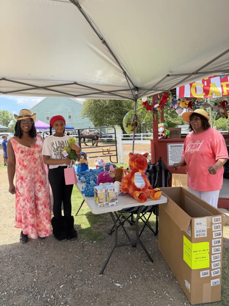 A young carnival guest receives a stuffed animal prize from volunteers at the prize booth