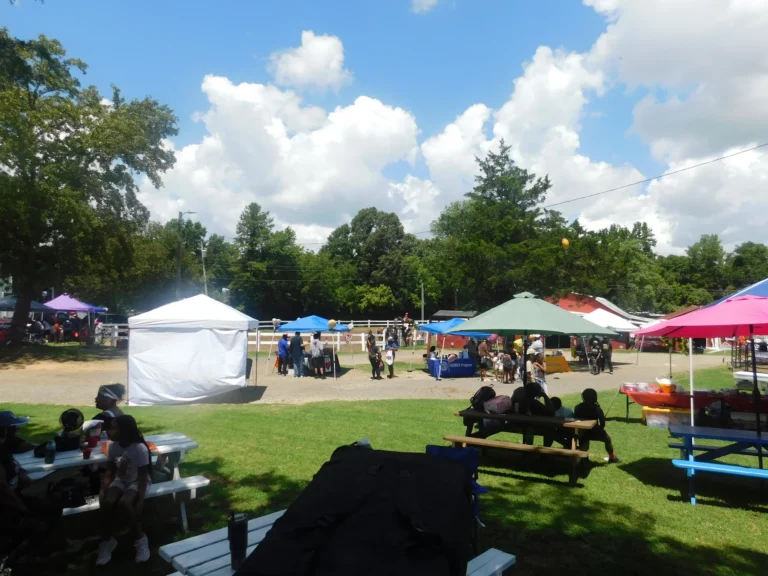 Guests relax at picnic tables across from the row of vendor canopies