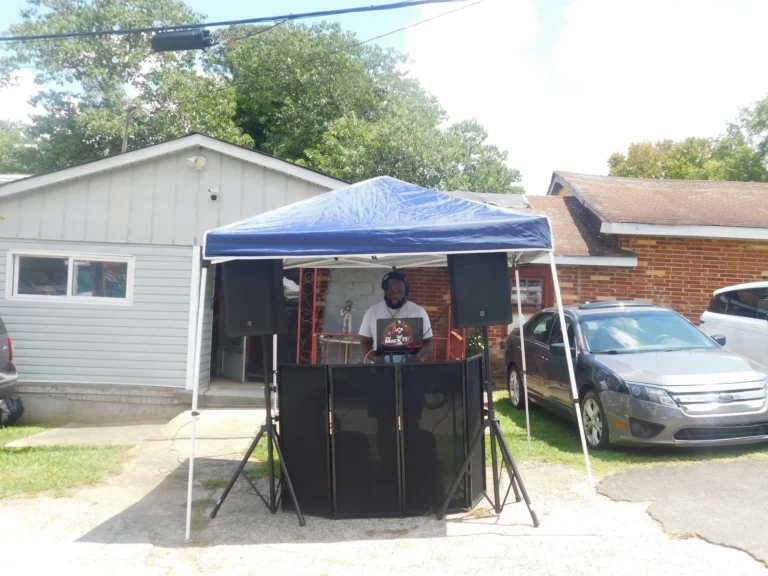 A DJ plays music from a canopy beside the building