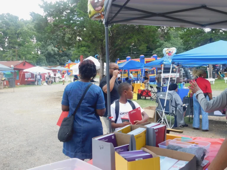 Families collect notebooks and school supplies from a vendor table