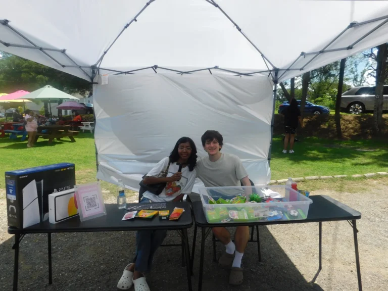 Two volunteers welcome guests at an information table
