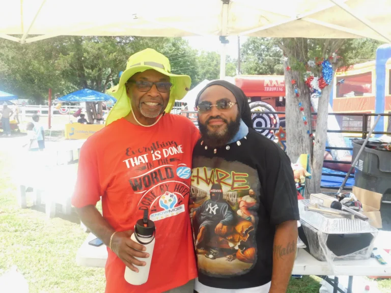 Two volunteers pose together in the shade