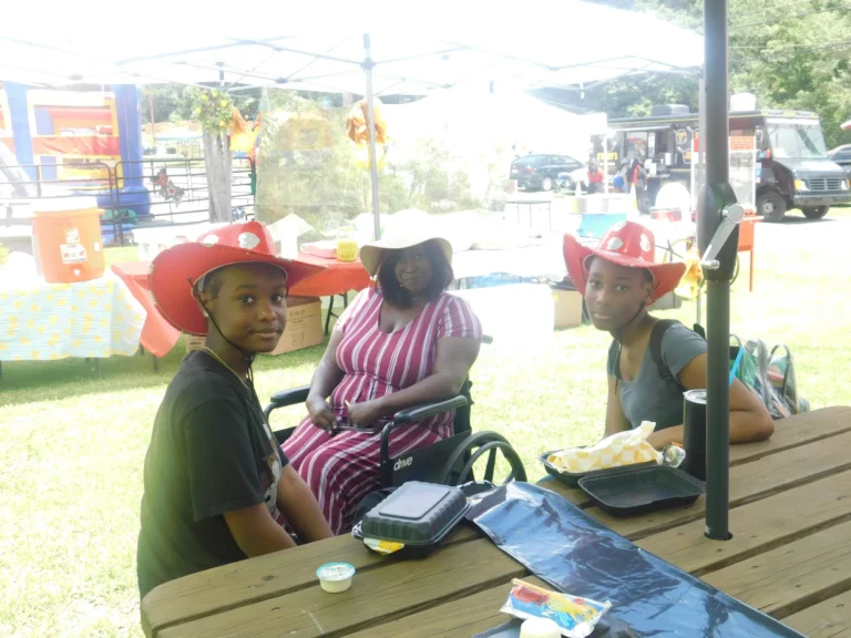 Guests wearing carnival hats sit together at a picnic table
