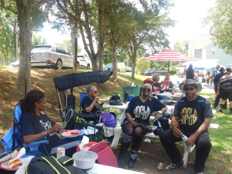 Guests relax in camp chairs in the shade