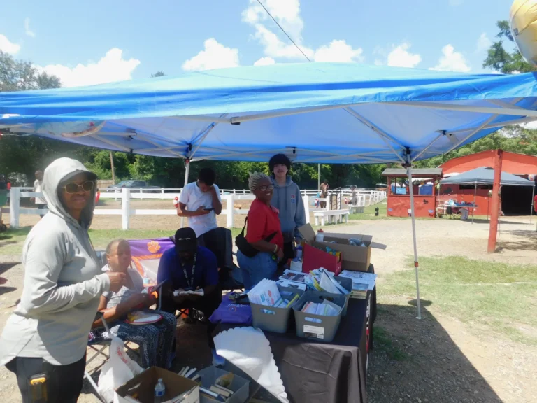 Volunteers work at a resource table under a blue canopy