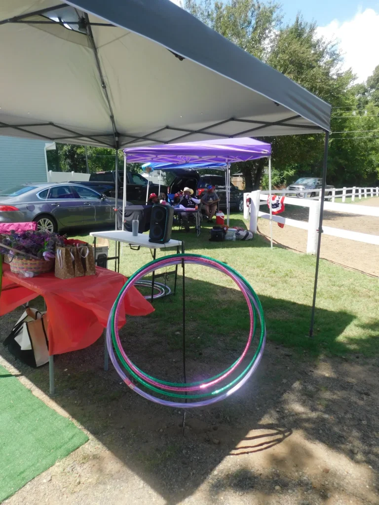 A prize table with hula hoops and gift baskets under the canopy